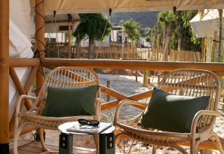 Dos sillas de mimbre y una mesa pequeña en la terraza del Glamping Comfort en Wecamp Cabo de Gata, España.