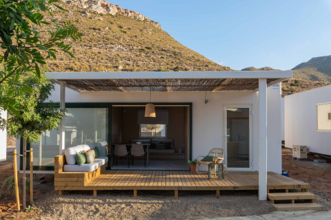 Mobil Home Family lodge met houten terras, zitgedeelte buiten en heuvelachtig uitzicht onder heldere lucht.