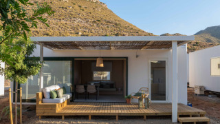 Mobil Home Family lodge met houten terras, zitgedeelte buiten en heuvelachtig uitzicht onder heldere lucht.