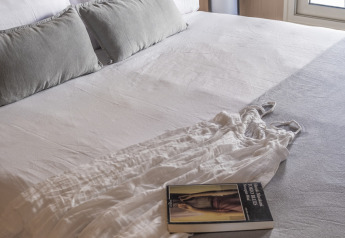 Camera da letto al Mobil Home Family, Wecamp Cabo de Gata, Spagna, letto rifatto con cuscini e libro sul plaid.
