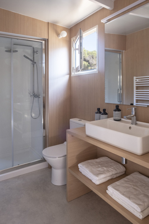 Moderne badkamer met douche, wastafel, toilet en handdoeken in Mobil Home Family, Wecamp Cabo de Gata, Spanje.