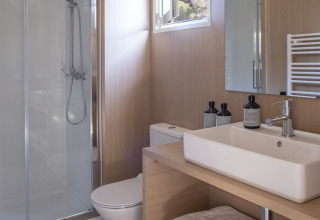 Moderne badkamer met douche, wastafel, toilet en handdoeken in Mobil Home Family, Wecamp Cabo de Gata, Spanje.