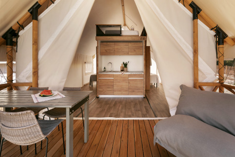 Interior de una tienda safari glamping con cocina, mesa de comedor y sofá en Wecamp Cabo de Gata en España.