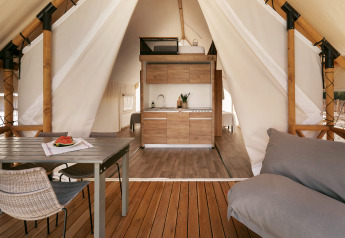 Interior de una tienda safari glamping con cocina, mesa de comedor y sofá en Wecamp Cabo de Gata en España.
