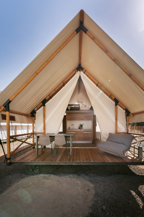 Tienda safari Glamping Family en Wecamp Cabo de Gata, España, terraza abierta con mesa y silla lounge.