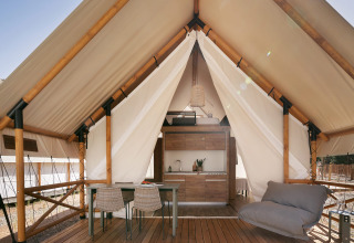 Tienda safari Glamping Family en Wecamp Cabo de Gata, España, terraza abierta con mesa y silla lounge.