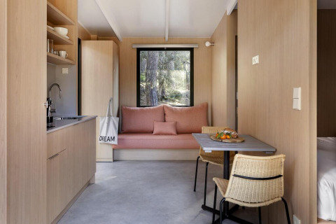 Interior moderno de Mobile home «Couple Plus» en Wecamp San Sebastián, con acabados en madera y sofá rosa.