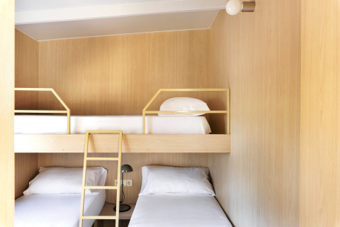 Moderne glamping accommodatie met houten wanden, stapelbedden en een lichte, minimalistische inrichting.