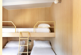 Moderne glamping accommodatie met houten wanden, stapelbedden en een lichte, minimalistische inrichting.