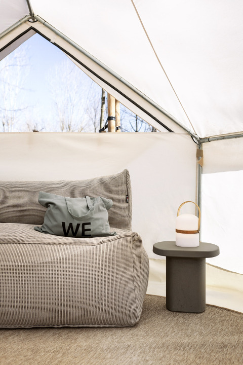 Interieur van de Bell Tent safaritent bij Wecamp Santa Cristina in Spanje, met zetel, kussen en lamp.