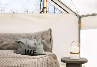 Interieur van de Bell Tent safaritent bij Wecamp Santa Cristina in Spanje, met zetel, kussen en lamp.