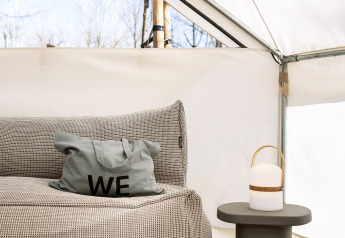 Interior of the Bell Tent safari tent at Wecamp Santa Cristina, Spain, featuring a sofa, cushion, and lamp.