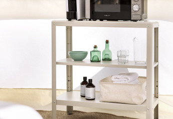 Shelving unit in a Bell Tent at Wecamp Santa Cristina, Spain with microwave, coffee maker and bottles.