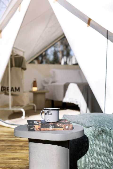 Bell Tent bij Wecamp Santa Cristina, Spanje, met tafeltje, boeken en mok in een sfeervolle setting.