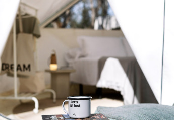 Glamping scene at Bell Tent, Wecamp Santa Cristina, Spain, featuring a table, books, and a 'Let's get lost' mug.