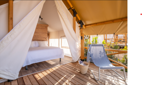 Safaritent met tweepersoonsbed en loungestoel bij Glamping Couple, Wecamp Santa Cristina, Spanje.