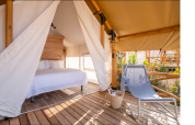 Safari tent with double bed and outdoor lounge chair at Glamping Couple, Wecamp Santa Cristina, Spain.