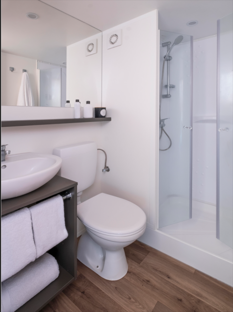 Moderne badkamer in een glamping tent met douche, toilet, wastafel en houtlook vloer bij Wecamp Santa Cristina.