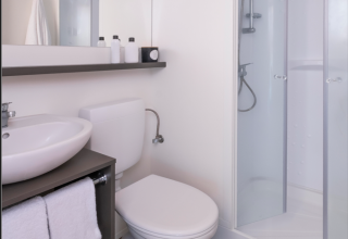 Moderne badkamer in een glamping tent met douche, toilet, wastafel en houtlook vloer bij Wecamp Santa Cristina.