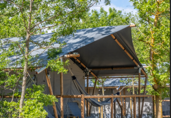 Tenda safari Lodge Family Plus con veranda e amaca, immersa tra gli alberi, ideale per una vacanza in famiglia.
