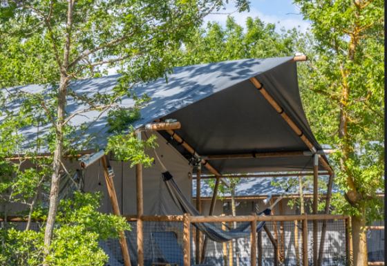 Safari tent Lodge Family Plus met veranda en hangmat, omringd door bomen, perfect voor een gezinsvakantie.