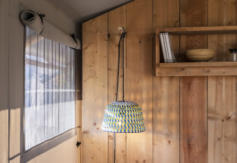 Interno della tenda safari Lodge Family Plus a Wecamp Santa Cristina, Spagna, con lampada sospesa.