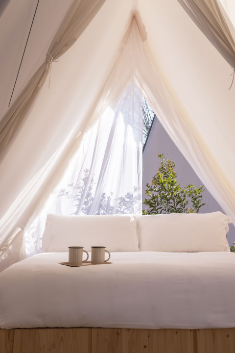 Licht safari tentbed met witte lakens en twee tassen bij Cabin Tent, Wecamp Santa Cristina, Spanje.