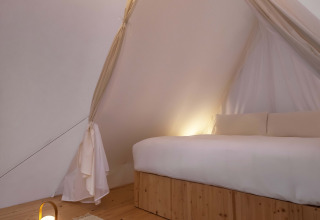 Interieur van de Cabin Tent bij Wecamp Santa Cristina in Spanje, met houten vloer en zachte verlichting.