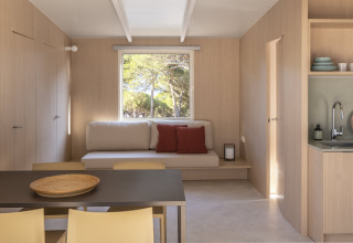 Lichte woonkamer in Mobil Home Family Plus bij Wecamp Santa Cristina, Spanje, met moderne houten inrichting.