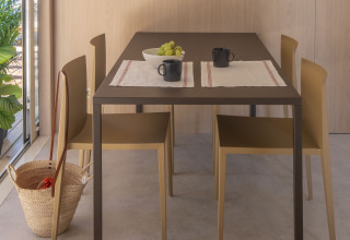 Eethoek in Mobil Home Family Plus bij Wecamp Santa Cristina, Spanje, met tafel, stoelen, mokken en fruit.