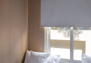 Kamer met twee eenpersoonsbedden, wit beddengoed, strohoed en raam in Mobil Home Family Plus in Spanje.