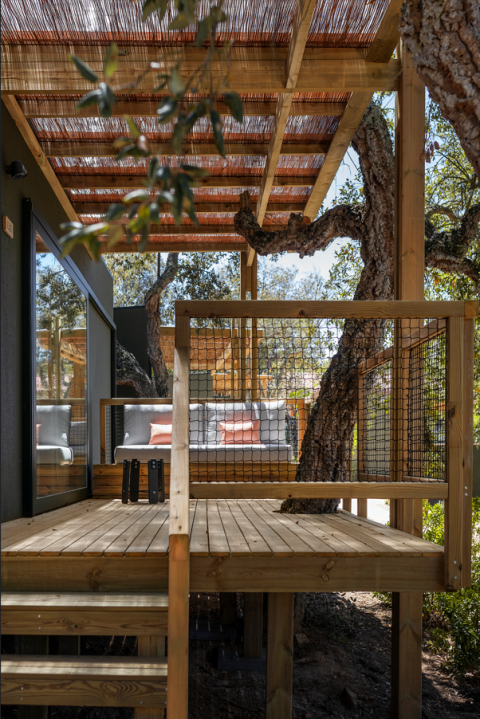 Houten terras met zithoek en omringende bomen bij Mobile Home Family in Wecamp Santa Cristina, Spanje.