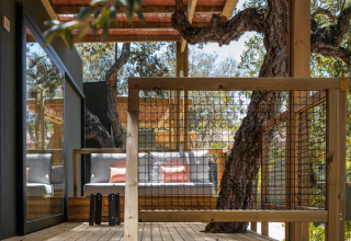 Houten terras met zithoek en omringende bomen bij Mobile Home Family in Wecamp Santa Cristina, Spanje.