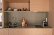 Kitchenette moderne avec armoires en bois clair, étagères ouvertes et cafetière au Wecamp Santa Cristina, Espagne.