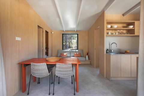 Interior minimalista de lodge en Mobile Home Family de Wecamp Santa Cristina, España, con comedor y cocina abierta.