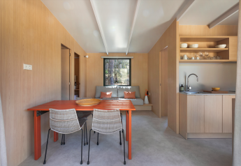 Interior minimalista de lodge en Mobile Home Family de Wecamp Santa Cristina, España, con comedor y cocina abierta.