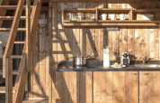 Interior of the Lodge Family Duplex safari tent featuring wooden kitchen and loft at Wecamp Santa Cristina.