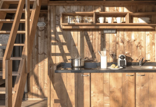 Interieur van de Lodge Family Duplex safaritent met houten keuken en slaapzolder bij Wecamp Santa Cristina.