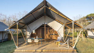Lodge Family Duplex safari tent with wooden deck, outdoor seating, and a relaxed nature setting.