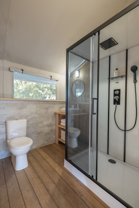 Moderne badkamer met houten vloer, douche en toilet in Family Duplex Lodge bij Wecamp Santa Cristina.