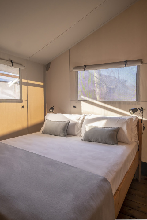 Slaapkamer met tweepersoonsbed en ramen in een safaritent Lodge Family Duplex bij Wecamp Santa Cristina, Spanje.