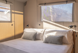 Slaapkamer met tweepersoonsbed en ramen in een safaritent Lodge Family Duplex bij Wecamp Santa Cristina, Spanje.