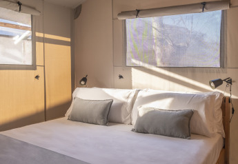 Dormitorio con cama doble y ventanas en una tienda safari Lodge Family Duplex en Wecamp Santa Cristina, España.