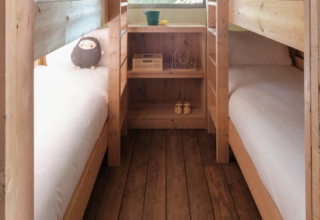 Gezellige slaapruimte met houten stapelbedden in een safaritent bij Wecamp Santa Cristina, Spanje.