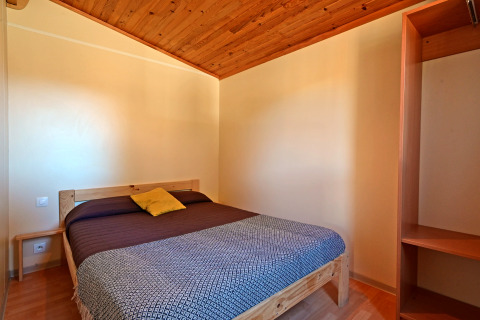 Chambre au Mobile Home Basic Family au Wecamp Pedraforca en Espagne, avec lit double et plafond en bois.