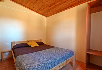 Camera da letto del Mobile Home Basic Family al Wecamp Pedraforca in Spagna, con letto matrimoniale e soffitto in legno.
