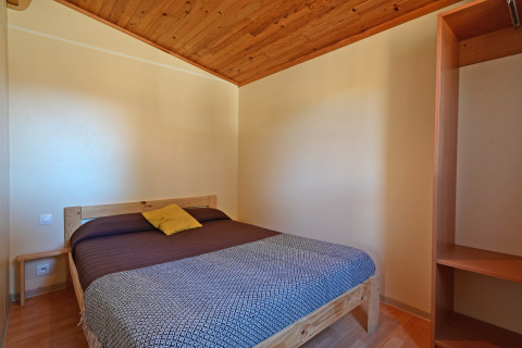 Camera da letto del Mobile Home Basic Family al Wecamp Pedraforca in Spagna, con letto matrimoniale e soffitto in legno.