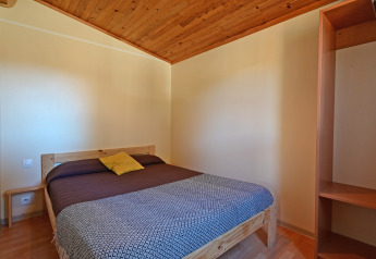 Dormitorio del Mobile Home Basic Family en Wecamp Pedraforca, España, con cama doble y techo de madera.
