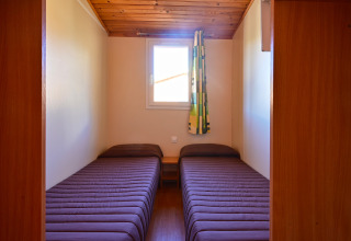 Dos camas individuales con ropa de cama marrón en una habitación pequeña de Mobile Home Basic Family, Wecamp Pedraforca, España.