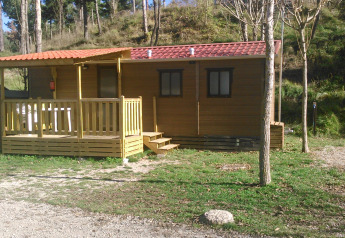 Mobile Home Basic Family en Wecamp Pedraforca, España, con terraza de madera y un entorno natural boscoso.